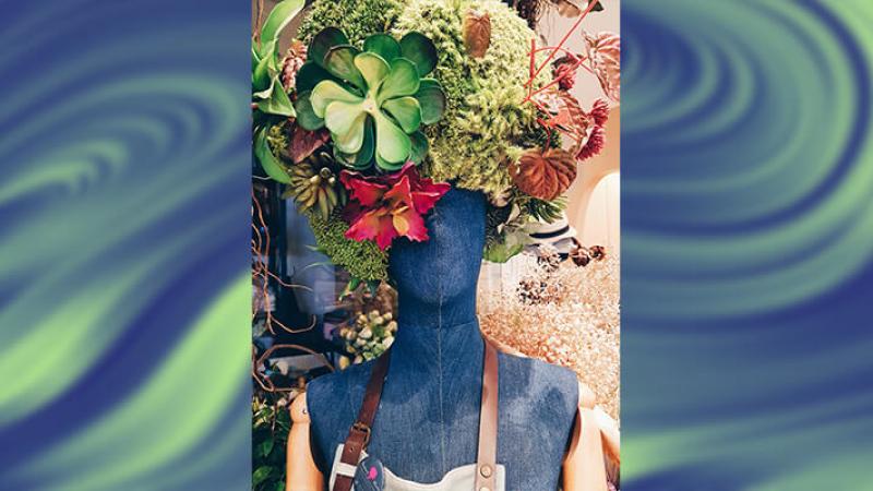A mannequine with a hat made out of flowers and other natural items.