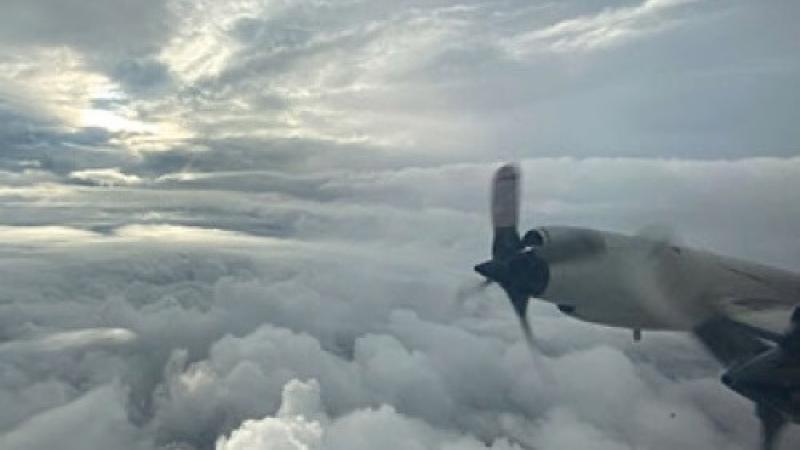 The wing of a plane with stormy clouds in the background.
