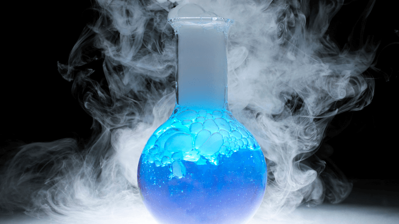 A beaker filled with blue liquid bubbles and steams