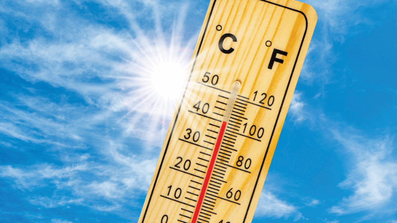A thermometer at 40°C/100°F on a blue sky with the sun shining.