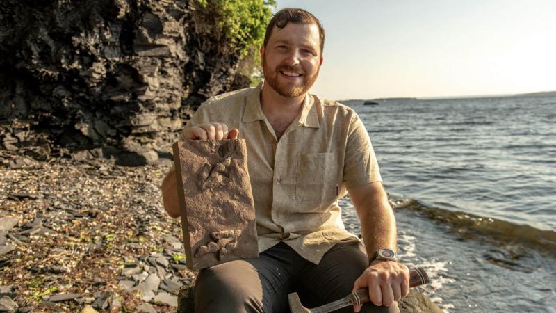 A paleontologist holding a fossil by the coast.