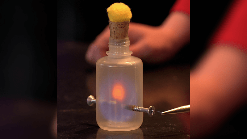 A plastic container with a yellow puff and a tesla coil shocking a screw.