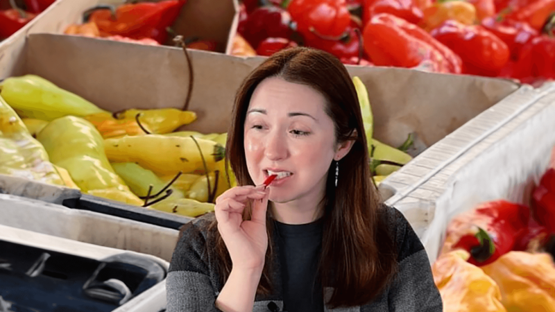 Alex Dainis taking a bite of a pepper with peppers in the background