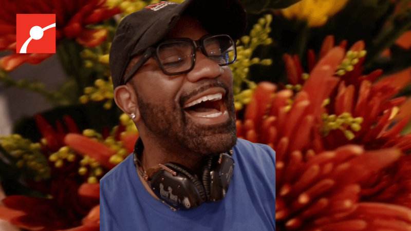 Maynard Okereke smiling with flowers behind him