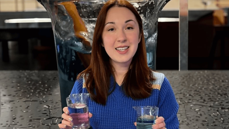 Alex Dainis holding up glasses with colored water 