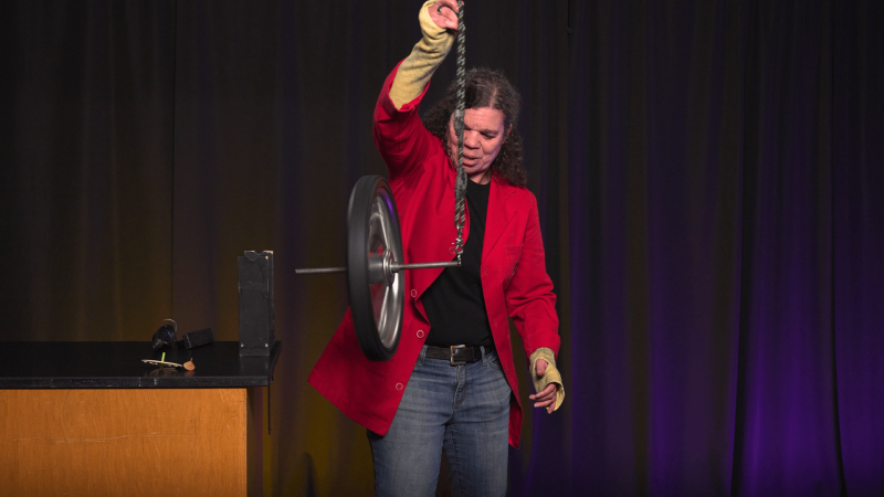 Museum Educator Jeannine holding a bike wheel from a rope