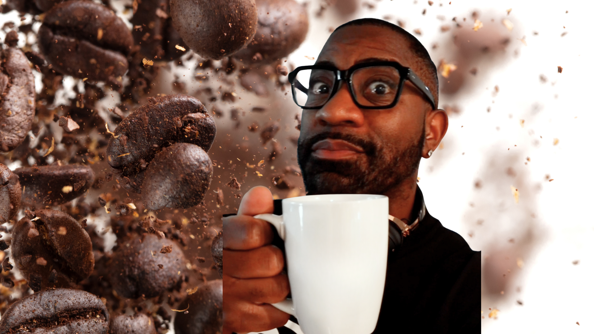 Maynard holding a white coffee mug with coffee beans in the background. 