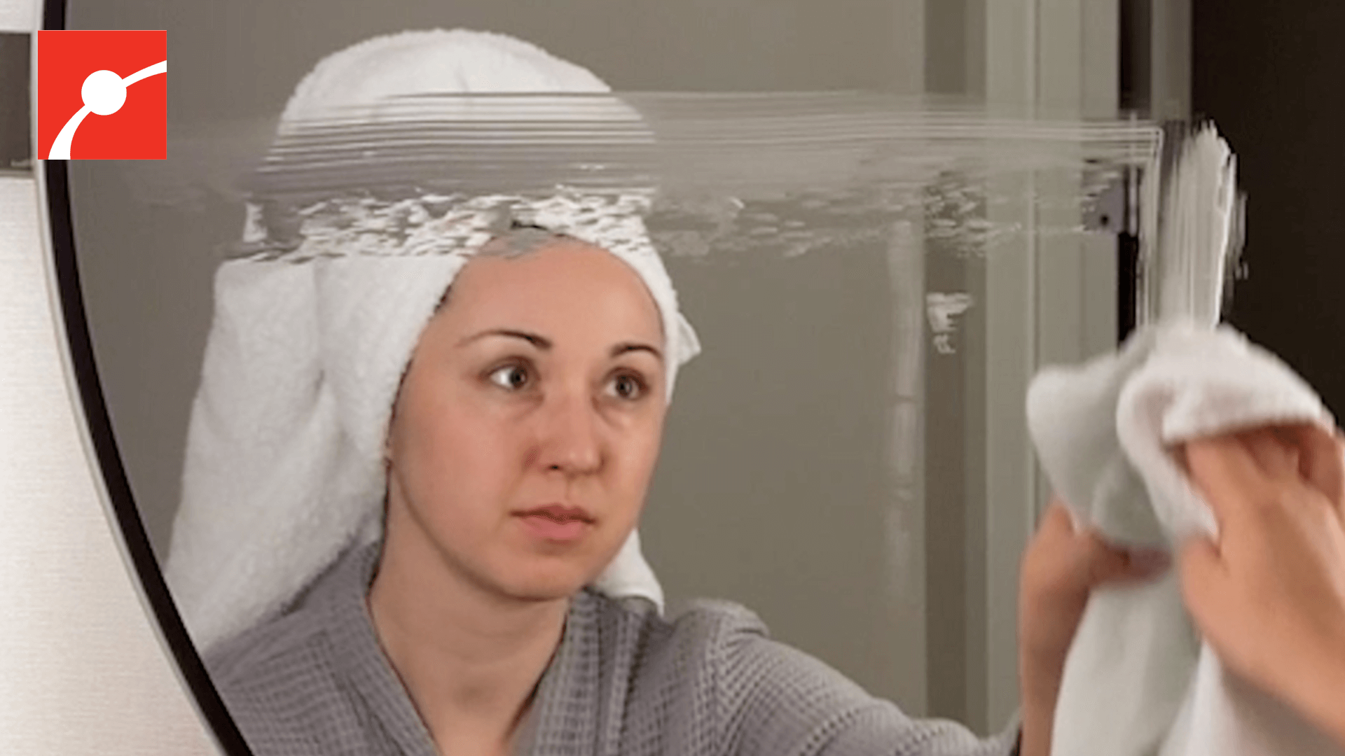 Alex Dainis with a towel on her head spreading shaving cream on a mirror. 