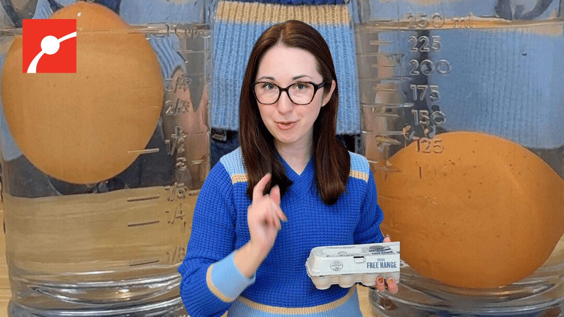 Alex Dainis holding a carton of eggs with eggs in a glass of water behind her