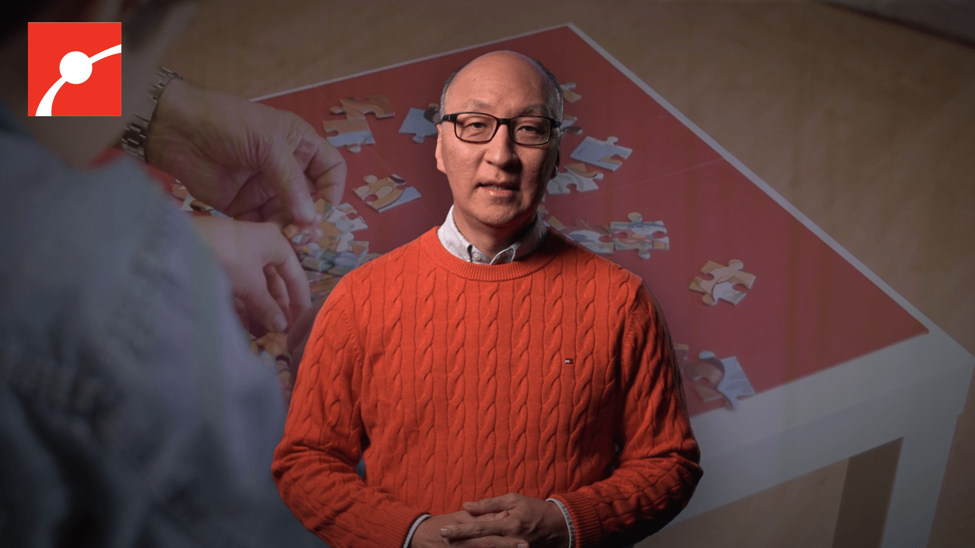 Insoo Hyun in front of an image of hands doing a puzzle