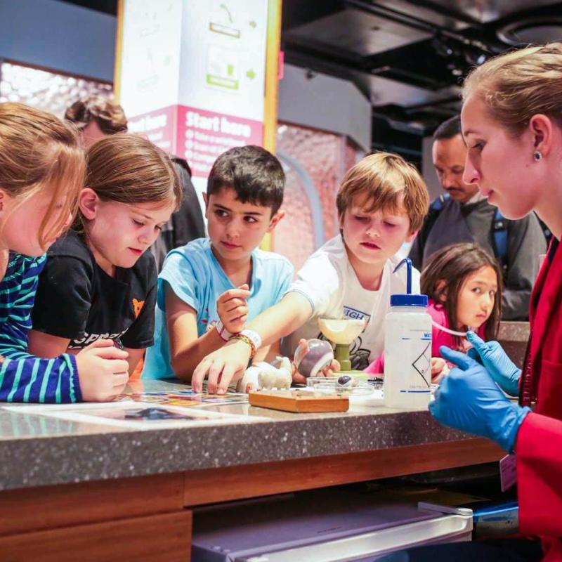 A group of children with and museum educator at the Biogen Exploration Hub