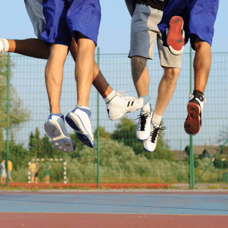 A group of people in sneakers and shorts jump on a basketball court
