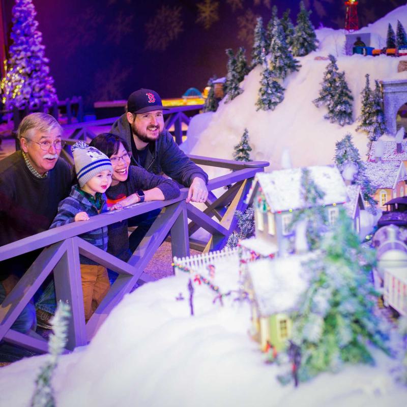 A family of Museum Members looking over a winter scene in All Aboard! Trains at Science Park,