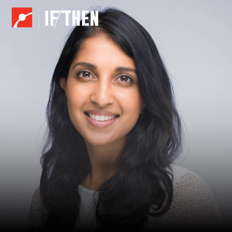 Dr. Ritu Raman smiles at the viewer in a white top in a grey background